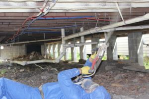 Contractor installing spray foam insulation in a crawlspace