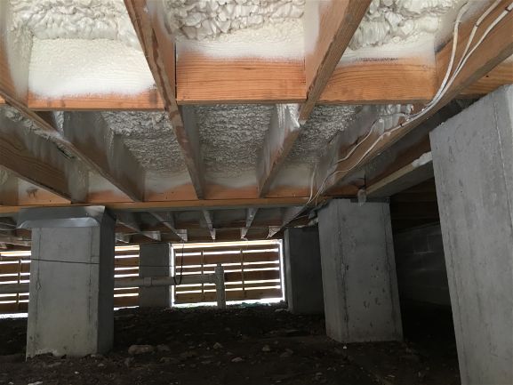 An image of subfloor with closed cell spray foam insulation installed.