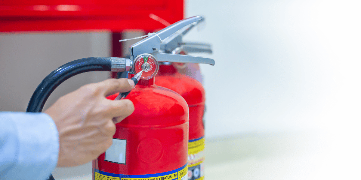 A person checking fire extinguishers during routine maintenance of fire safety equipment