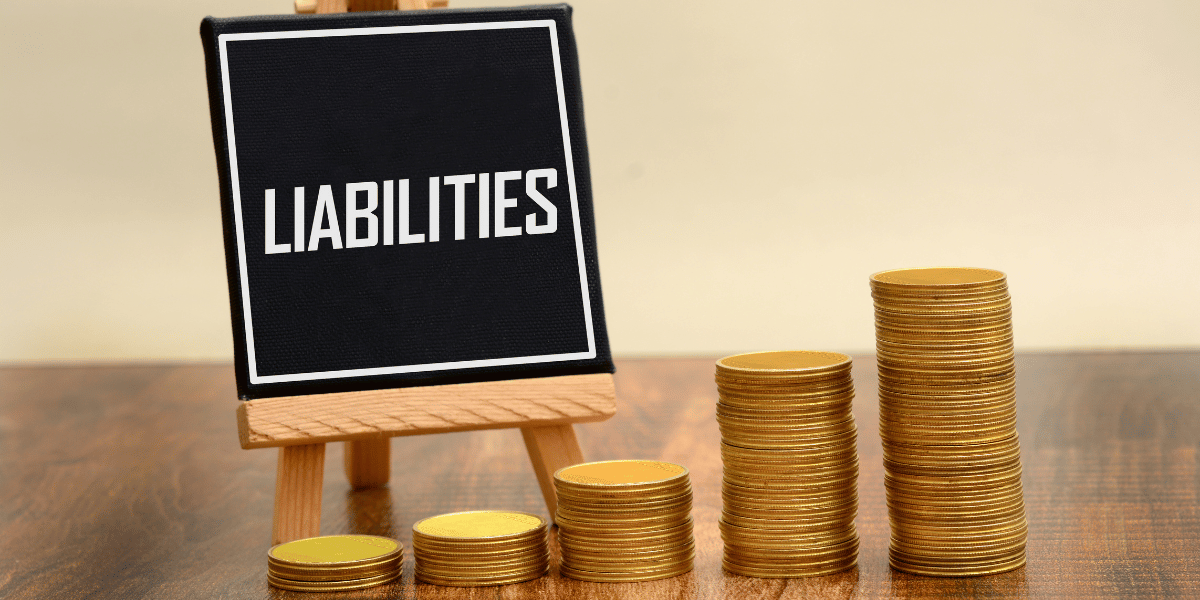 A small sign on an easel that says liabilities with coins around it