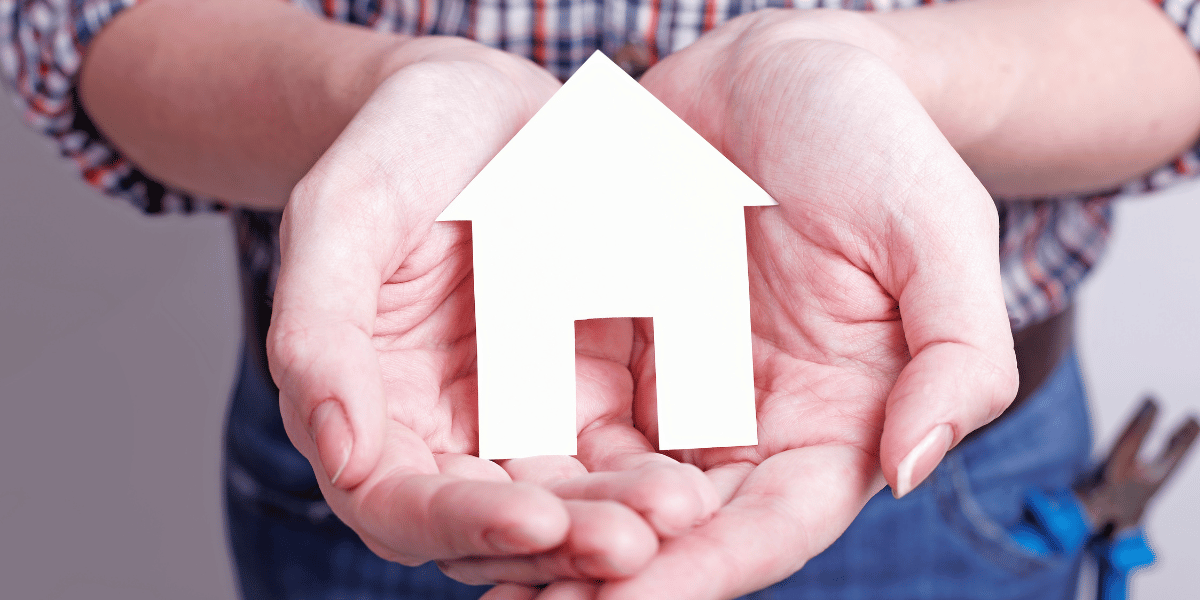 A person holding a small  paper cutout of a home to represent protecting your home with an inspection