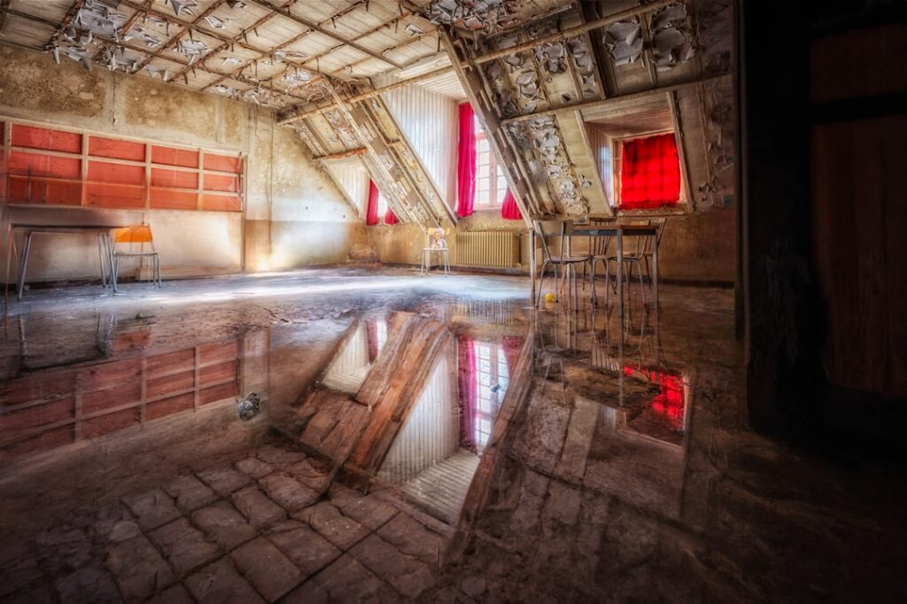 Dark and dusty attic with a dramatic beam of bright sunlight shining through a small window, illuminating dust particles i...