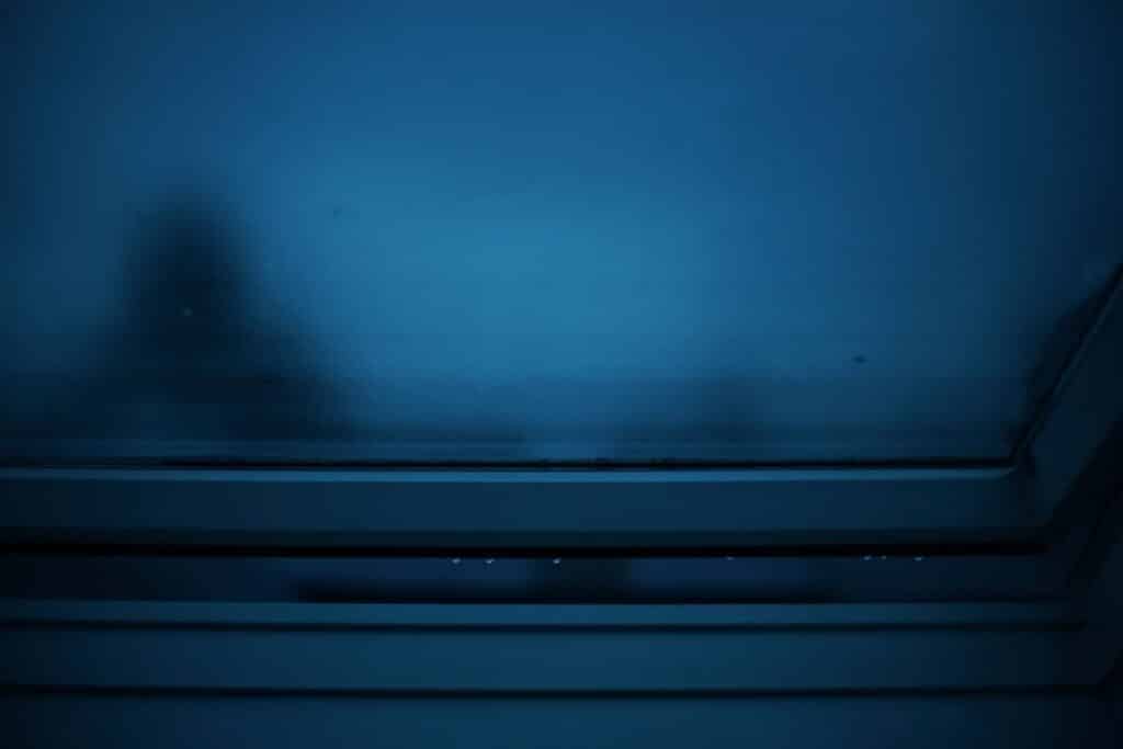 Home inspector shines a flashlight into a dark, dusty attic, revealing old wooden beams and insulation, representing a tho...