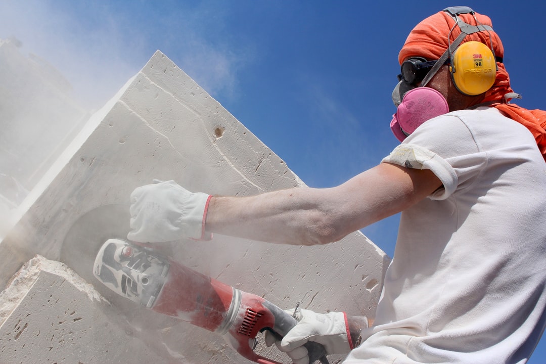 A construction professional in full protective gear applying expanding spray foam insulation inside a wall, a modern solution for home stability and energy efficiency.