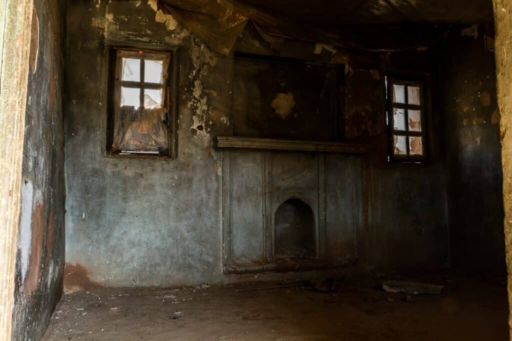 Interior of a home being renovated after flood damage, with exposed wooden wall studs and debris on the floor under dramat...