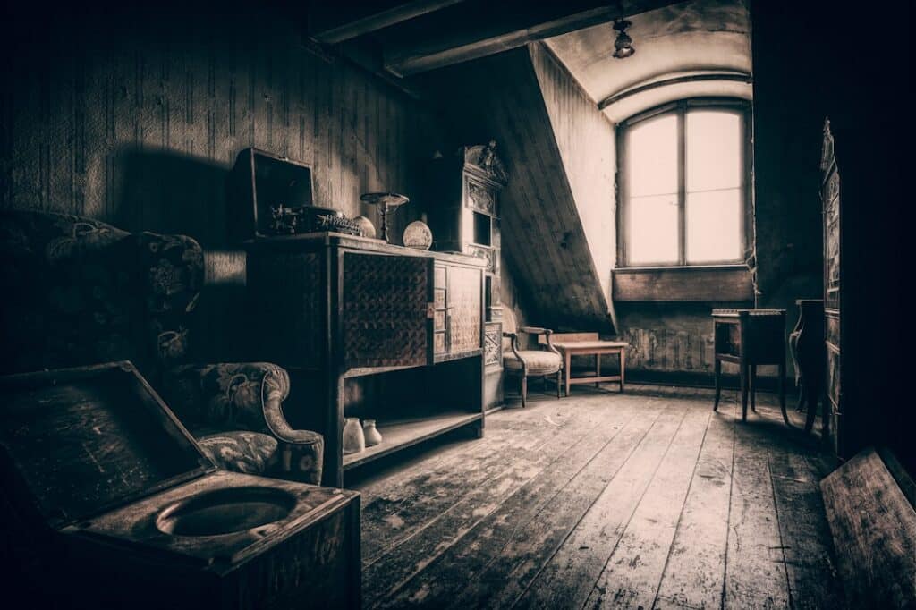 Sunlight streams through the dusty rafters of a hot, leaky attic, highlighting the source of the stack effect in a home.