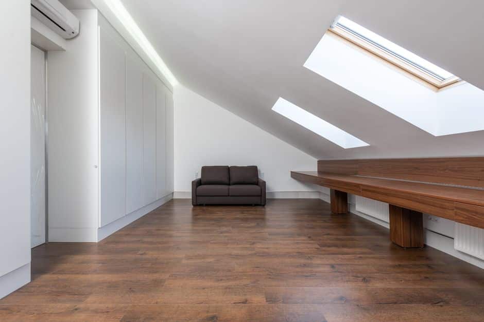 A bright, clean residential attic showing the finished application of white spray foam insulation covering the rafters and ceiling, creating an energy-efficient space.