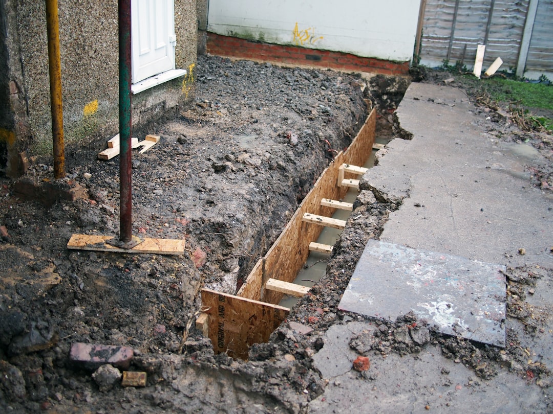 A close-up view of damp, weathered wooden floor joists in the crawlspace of a house, indicating a moisture control problem.