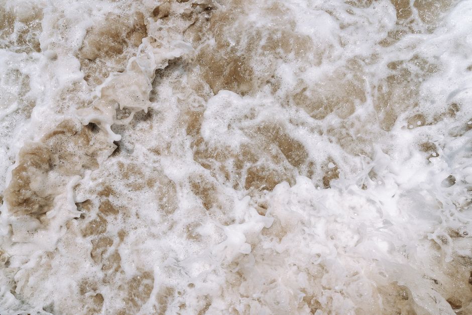 A detailed macro shot of cured white spray foam insulation, showing its unique, rigid, and bumpy texture.