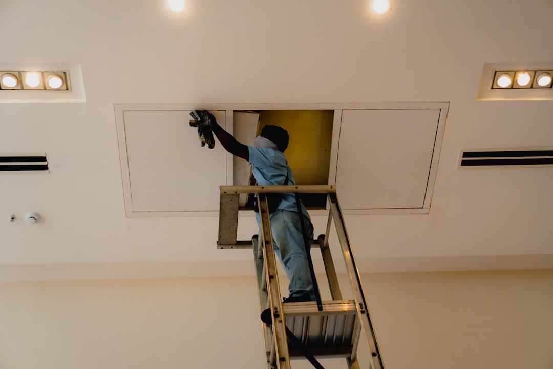 A professional insulation contractor in full protective gear applying spray foam insulation between studs in a new construction home.