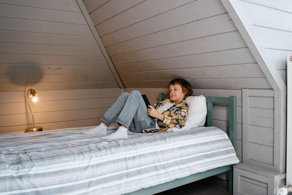 A professional contractor in protective gear meticulously applies modern spray foam insulation to attic rafters, showcasing a high-quality home energy solution.
