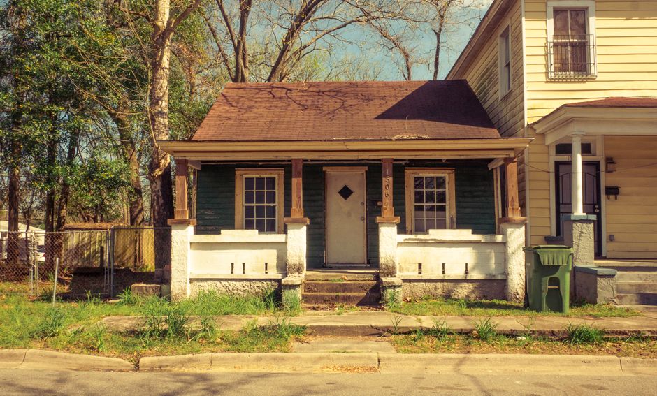 A classic, colorful Louisiana shotgun-style house under the bright, hazy sun of a humid summer day, representing the unique climate challenges for homeowners in the region.