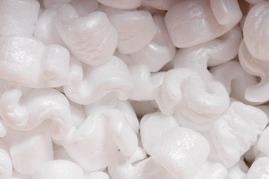 Close-up shot of deep, fluffy pink fiberglass insulation in a residential attic, visually representing the low-density 'fl...