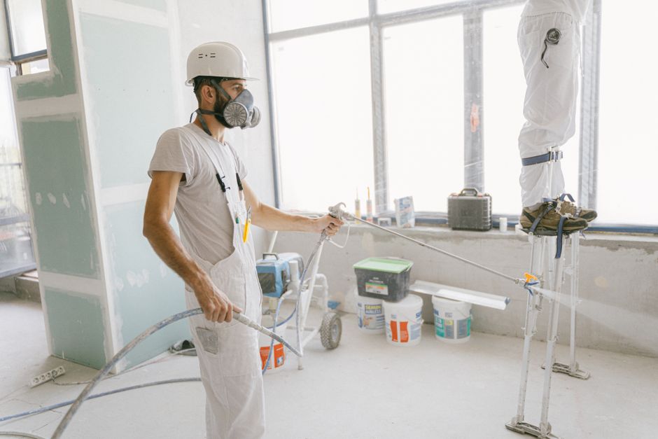 A construction worker in protective gear professionally applying closed-cell spray foam insulation to the interior wall studs of a new home build.