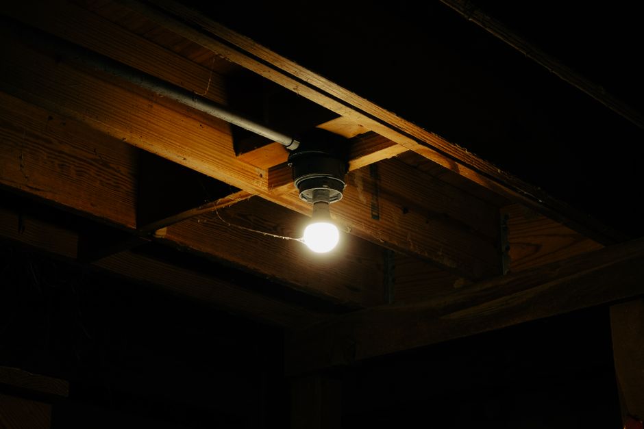 Detailed close-up shot of old, matted, and discolored insulation in a dark attic, showing signs of decay and potential moi...