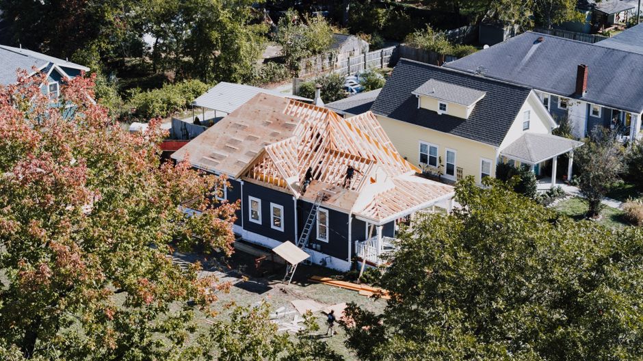 A modern home elevated on stilts or a raised foundation, under construction on a bright day, representing building practices for flood-prone areas like Louisiana.