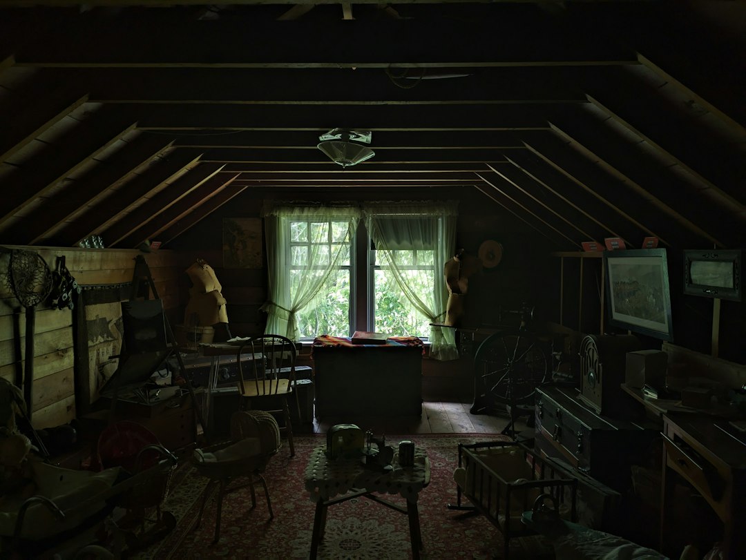 A professional contractor wearing a headlamp shines a flashlight on the insulation in a dark attic, suggesting the discovery of a problem.